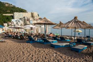 a group of people sitting on a beach with umbrellas at Guest House Plan B in Rafailovici