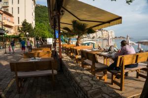 een persoon aan een tafel in een openluchtrestaurant bij Guest House Plan B in Rafailovici
