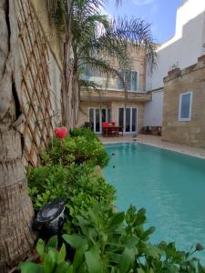 a swimming pool in front of a house with a palm tree at The Luxury Home - Next to airport! in Kirkop