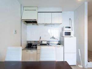 a kitchen with white cabinets and a white refrigerator at Reality Hakata 2 in Fukuoka