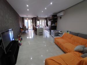 a living room with an orange couch and a kitchen at The Luxury Home - Next to airport! in Kirkop