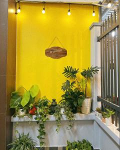 a yellow wall with plants and a sign on it at K-HOUSE Homesaty Phan Thiết in Ấp Bình Hưng +27 photos