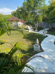 a garden with a stone statue on a path at Villa Samalas Resort and Restaurant in Gili Meno