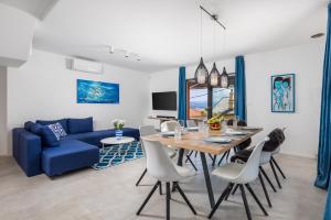 uma sala de estar com um sofá azul e uma mesa e cadeiras em Villa Lomida Opatija em Opatija