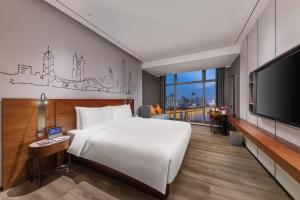 um quarto de hotel com uma cama grande e uma televisão de ecrã plano em UrCove By Hyatt ShenZhen Bay em Shenzhen