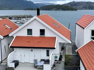een wit gebouw met oranje daken naast een waterlichaam bij Holiday home Huglo II in Nordhuglo