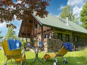 una casa con dos sillas y una mesa frente a ella en Berghütte Schwarzenberg, Urlaub in mitten der Natur, en Schwarzenberg am Bohmerwald