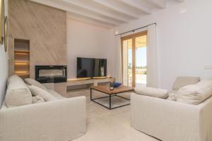 a living room with two white couches and a tv at Can Mosca in Cala Mendia