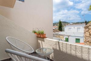 uma varanda com uma mesa de vidro e cadeiras num edifício em Ethereal Stay em Spetses