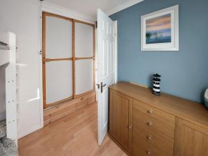 a bedroom with blue walls and a wooden dresser at Casabella in Hemsby