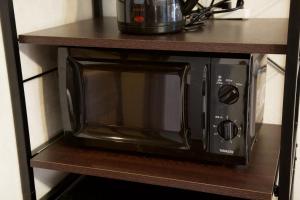 a microwave oven sitting on a shelf in a kitchen at 大井町アパートメントホテル豊強ビル301 in Tokyo