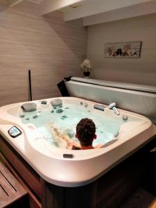 uma pessoa numa banheira de hidromassagem na casa de banho em Chambre d'hôtes Comme une évidence em Clairvaux-les-Lacs