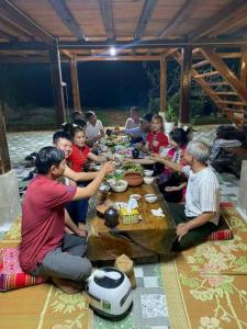 Un gruppo di persone seduti intorno a un tavolo che mangiano di Homestay view núi cực đẹp a Cham Ta Lao