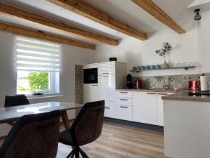 a kitchen with white cabinets and a table with chairs at Haus Mariechen in Frielendorf