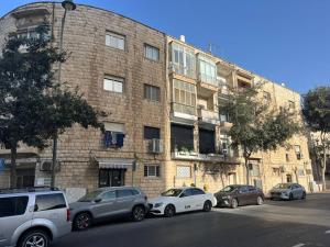 um edifício de tijolos com carros estacionados em frente em Rosa’s place em Jerusalém