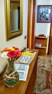 a vase of flowers on a wooden counter with a mirror at B&B L'Aquila in LʼAquila
