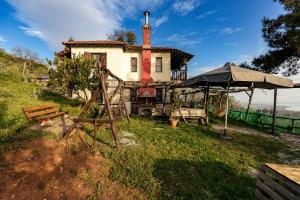 an old house with an umbrella and a playground at Halatsogiannis Mansion in Palaios Panteleimon