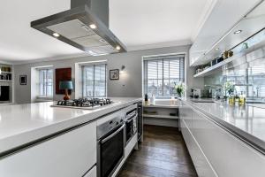 une grande cuisine avec des comptoirs blancs et un évier dans l'établissement Woodbridge House Apartment, à Londres