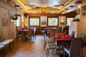 een restaurant met rode tafels en stoelen en ramen bij Al Mughetto in Auronzo di Cadore