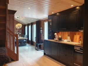 cocina con armarios negros y comedor en Wonderful cabin with amazing mountain - view, en Lifjell