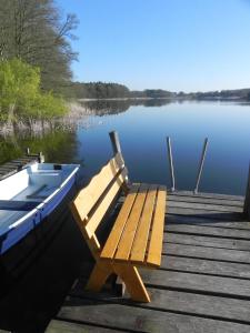un quai en bois avec un banc à côté d'un bateau dans l'établissement Ferienwohnungen am See, à Vietgest