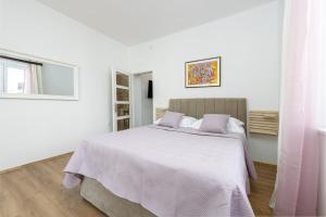 ein weißes Schlafzimmer mit einem großen Bett mit lila Kissen in der Unterkunft Apartment Iva in Dubrovnik