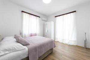 ein weißes Schlafzimmer mit einem Bett und zwei Fenstern in der Unterkunft Apartment Iva in Dubrovnik