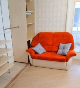 an orange chair with two pillows sitting in a room at 2 кімнатні апартаменти в центрі Дніпра, поруч Мечнікова для ЗСУ знижка in Dnipro