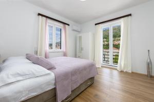 ein weißes Schlafzimmer mit einem Bett und zwei Fenstern in der Unterkunft Apartment Iva in Dubrovnik + 37 Fotos