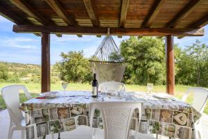 einen Tisch mit weißen Stühlen und einem Kronleuchter in der Unterkunft La Collina degli Ulivi in Bari Sardo