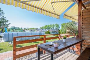 einem Holztisch auf einer Terrasse mit einer Bank und einem Regenschirm in der Unterkunft Baltic Resort in Mielno