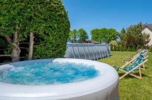 a large tub filled with blue water next to a chair at Baltic Resort in Mielno