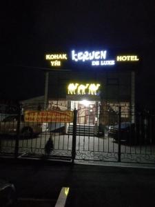un hotel con letreros de neón delante de él por la noche en Keruen Deluxe, en Taraz