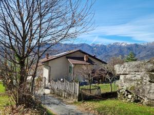 a small house with a fence and mountains in the background at Casa Monte Bracco in Rifreddo