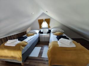 a attic room with two beds and a couch at Domki pod klonem in Studzienice