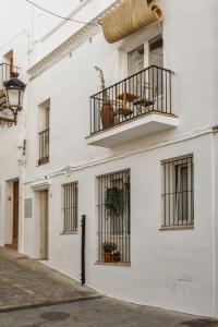 een wit gebouw met ramen en een balkon bij Casa Uva - Boutique Guest House in Vejer de la Frontera