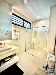 ein weißes Bad mit einer Dusche und einem Waschbecken in der Unterkunft Batu Ferringhi Luxurious Modern Designed 5BR House in Batu Feringgi