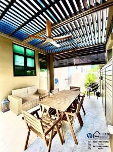 patio z drewnianym stołem i krzesłami w obiekcie Batu Ferringhi Luxurious Modern Designed 5BR House w mieście Batu Ferringhi