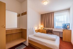 グラーツにあるホテル ケルン ブアムのベッドとデスクが備わるホテルルームです。