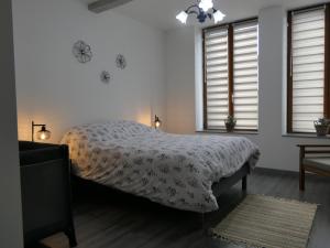 a bedroom with a bed with a comforter and two windows at L'Escale des remparts in Rocroi