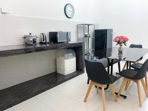 a kitchen with a table and chairs and a clock at Sulong Inn - Private Pool Homestay in Kuantan, Pantai Sepat in Kuantan