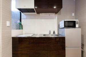 a small kitchen with a sink and a microwave at Shiki Homes HIGOYA 肥後屋 in Kyoto