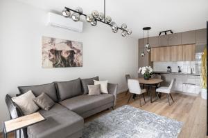 ein Wohnzimmer mit einem grauen Sofa und einem Tisch in der Unterkunft Žalia kopa Metropolis Vilnius in Vilnius