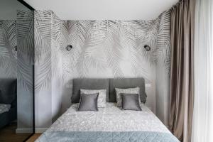 ein Schlafzimmer mit einem Bett und einer Wand mit einem Palmenmilch in der Unterkunft Žalia kopa Metropolis Vilnius in Vilnius