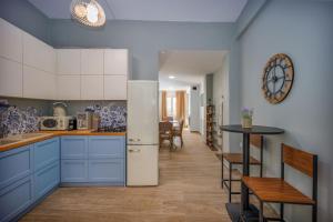a kitchen with blue cabinets and a table and a clock at Central Art Maisonette by Estia in Heraklio Town