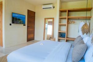 Olea Villas Resort في كوتا لومبوك: غرفة نوم بسرير ابيض وتلفزيون
