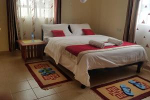 1 dormitorio con 1 cama grande y zapatillas. en La petals hideaway house-Machakos, en Machakos