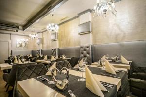 a dining room with tables and chairs and chandeliers at Teátrum Boutique Hotel in Győr