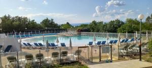 une grande piscine avec des chaises et des parasols dans l'établissement Duplex (5pers) dans village vacances en Ardèche, à Grospierres