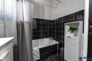 Room Riviera 4 Aéroport Wifi Climatisation Partagé في نيس: حمام مع حوض استحمام أبيض وجدار من البلاط الأسود